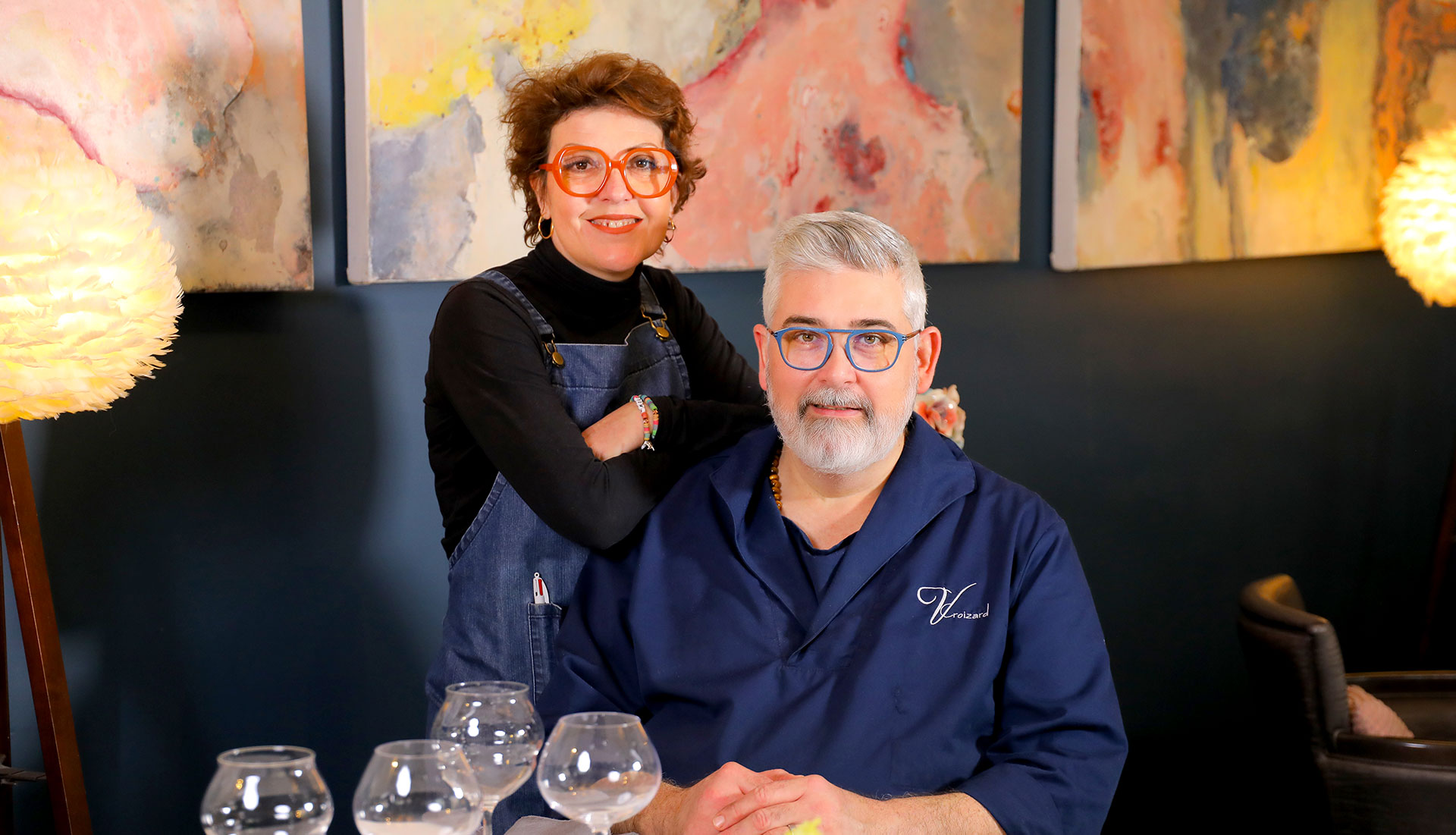Vincent Croizard et madame Croizard posant dans la salle du restaurant, devant des œuvres d'art contemporain